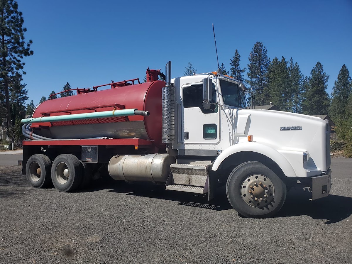 The Nine Mile Septic pump truck, red tank and white cab, parked on a sunny rural lot